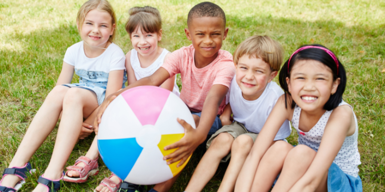 Group of kids in park together with a beach ball
